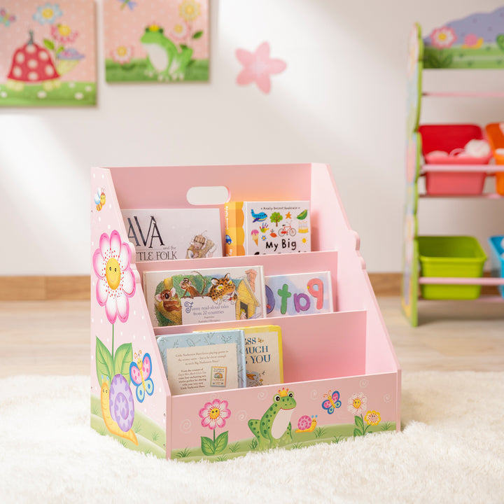 A Fantasy Fields Kids Painted Wooden Magic Garden 3-Tiered Bookshelf, Pink in a playroom.