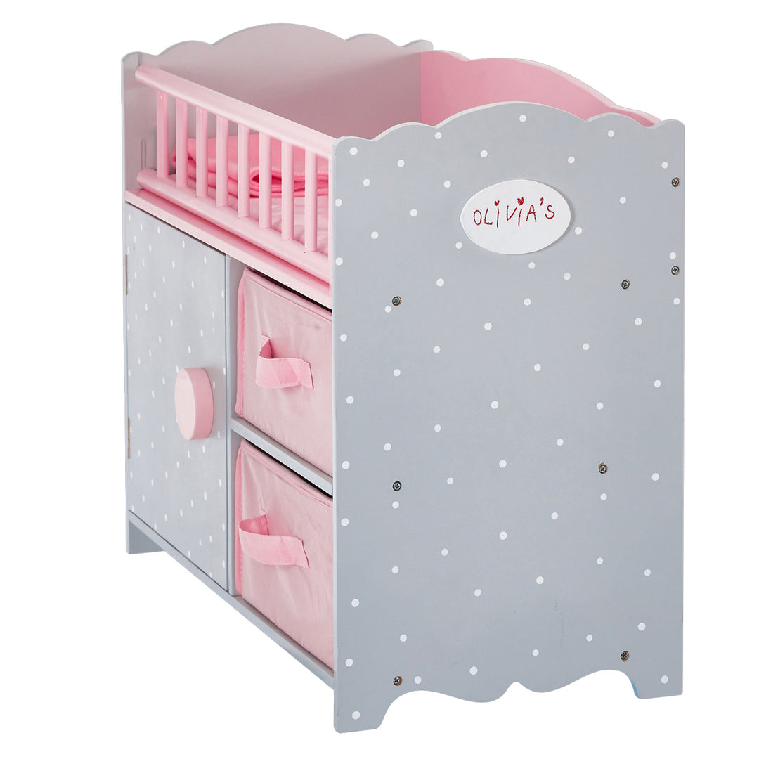 A view of the footboard of a gray baby doll crib with white polka dots and pink accents.