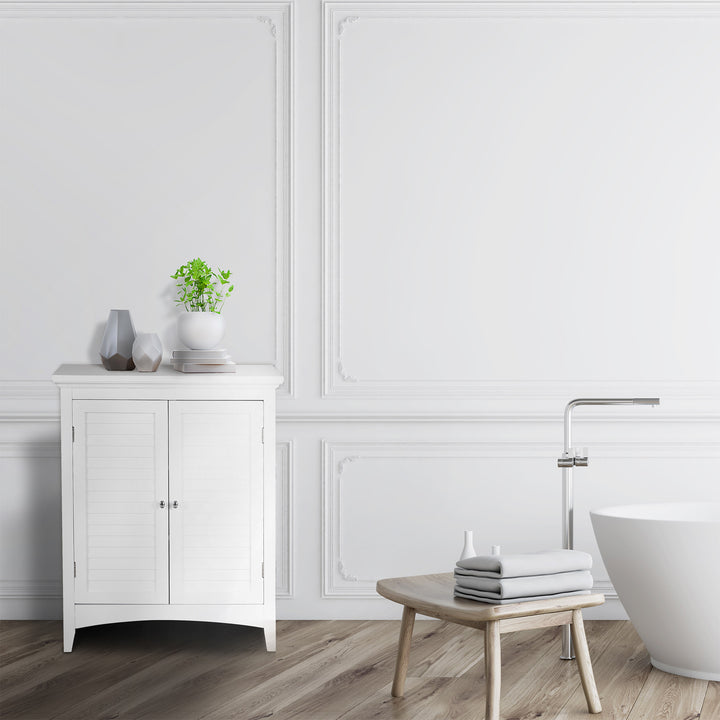A minimalist white bathroom with a freestanding bathtub, wooden stool, and a White Glancy 2-Door Floor Cabinet with Louvered Doors, Chrome Knobs