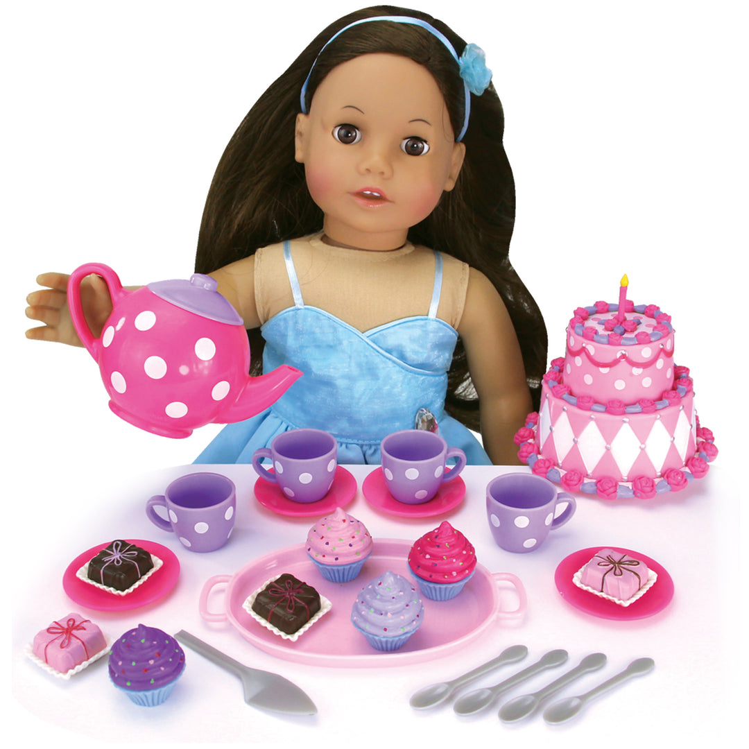 An 18" doll with brunette hair has a pink teapot in a pouring angle towards 4 teacups with scattered treats all over the table.