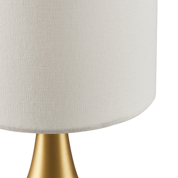 A Teamson Home Sarah 15" Modern Metal Table Lamp with Touch Switch and Cream Shade, Polished Brass with a white shade and contemporary design.