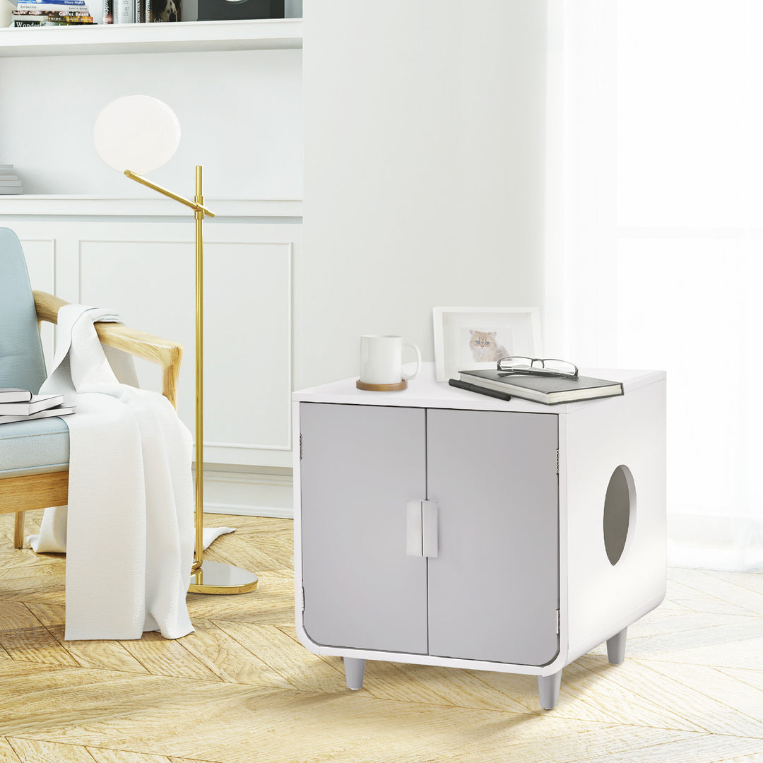 An alpine white cat litter box enclosure and side table sat next to a chair with items on top, serving also as an end table.