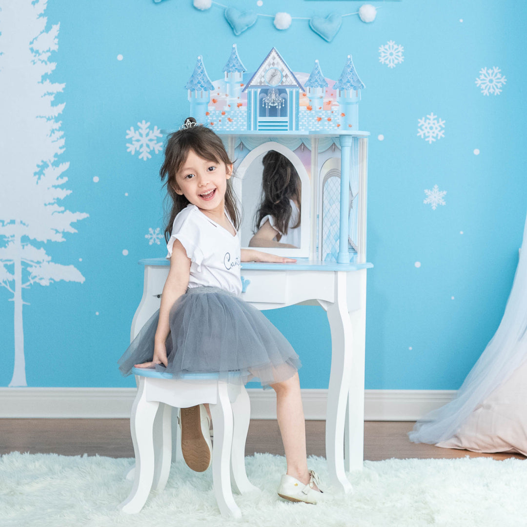 A little girl sitting at the white and blue vanity set with mirror and castle ballroom for 12" dolls.
