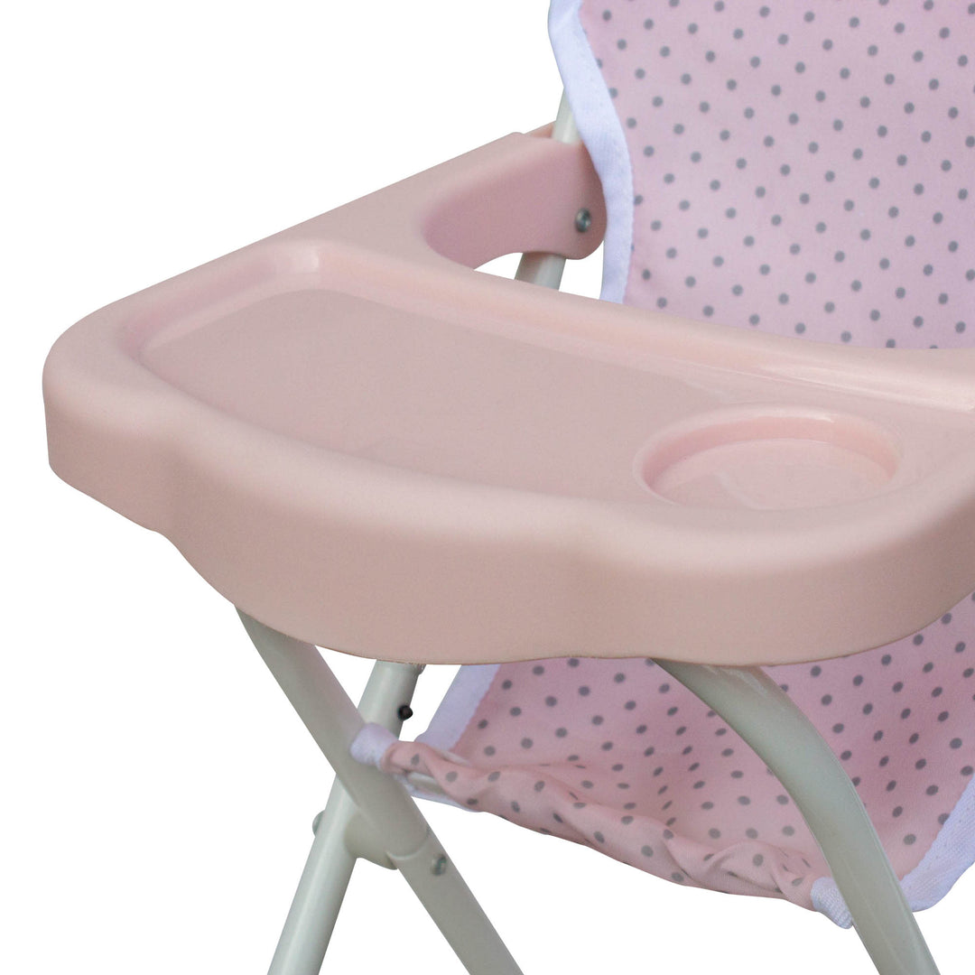 A close-up of a pink plastic tray with a cup holder on a pink and white baby doll stroller.