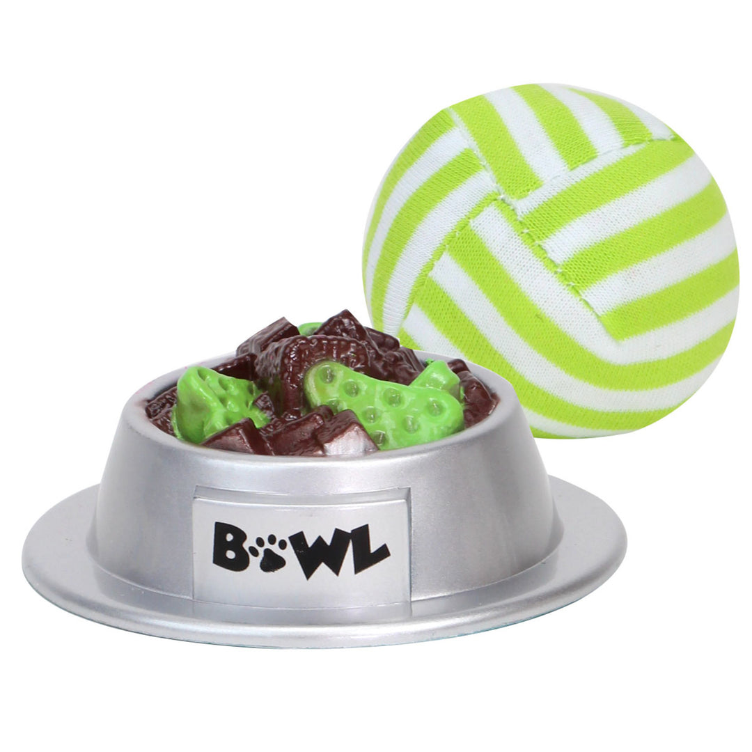 A silver bowl of faux pet food and a green and white ball to play fetch with the siamese kitten.