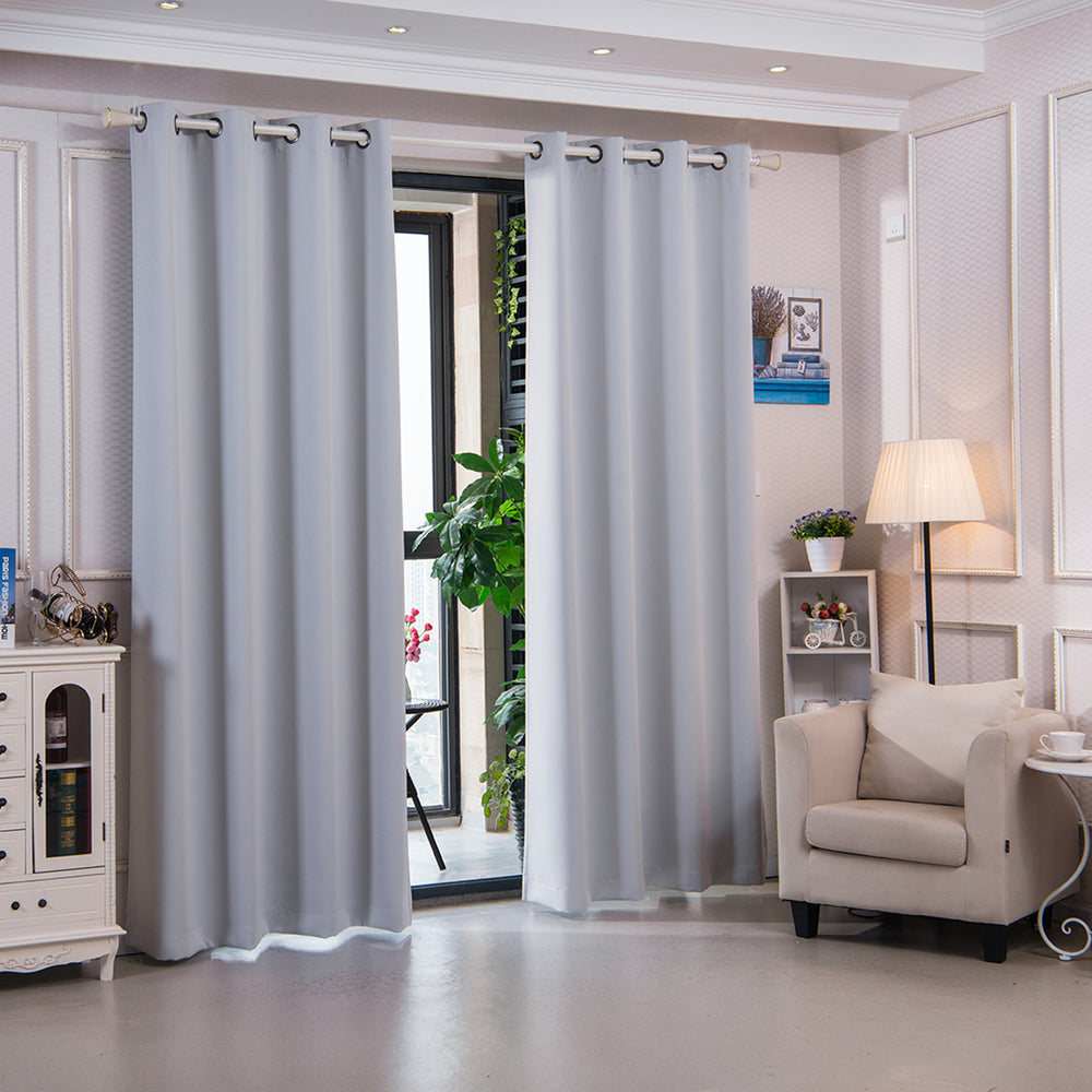 Teamson Home 96" Corinth Premium Solid Insulated Thermal Blackout Window Curtain Panels with Grommets, Cloud Gray hanging in front of a window panel in a neatly furnished room with an armchair and standing lamp.
