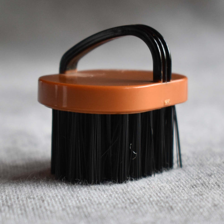 A close-up of a brush sized for an 18" doll's hand.