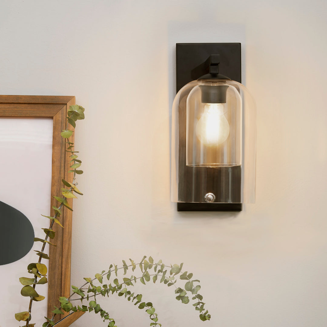 Teamson Home Matte Black Wall Sconce with Double Glass Shade mounted next to a frame