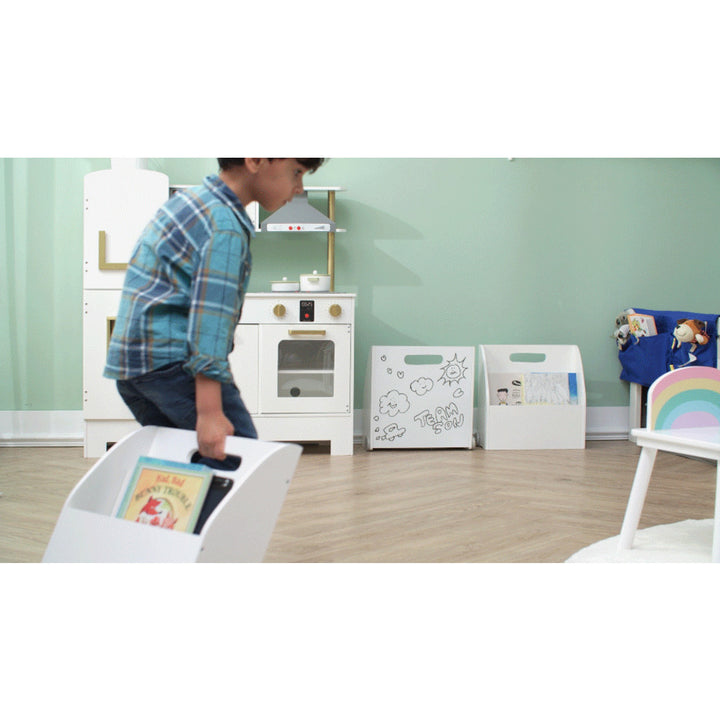 A young boy is playing with a Fantasy Fields Kids Portable Bookcase Set of 3 with Magnetic Dry Erase Whiteboard, White in a room.