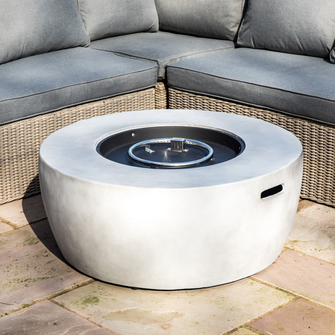 Teamson Home 36" Outdoor Round Propane Gas Fire Pit with Faux Concrete Base, Gray positioned on a patio between outdoor sectional couches.