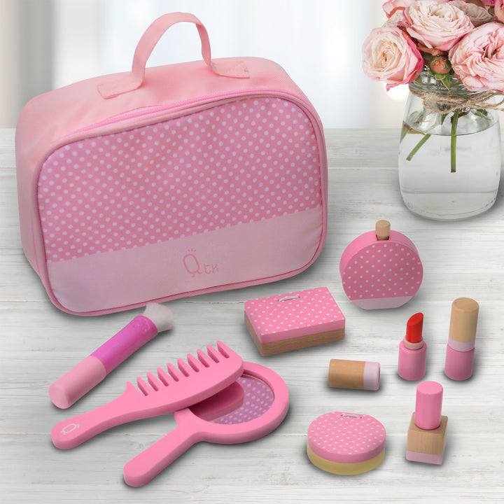 A pretend make-up kit with accessories laid out on a table: brush, comb, hand-held mirror, eyeshadow pallet, perfume, two lipstick tubes, compact and nail polish.