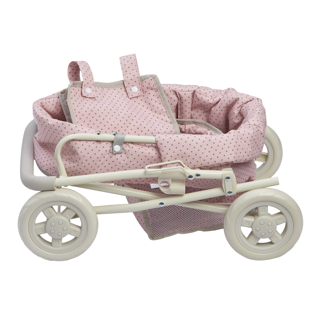 The baby doll stroller collapsed for storage, pink with gray polka dots and a white frame and wheels.