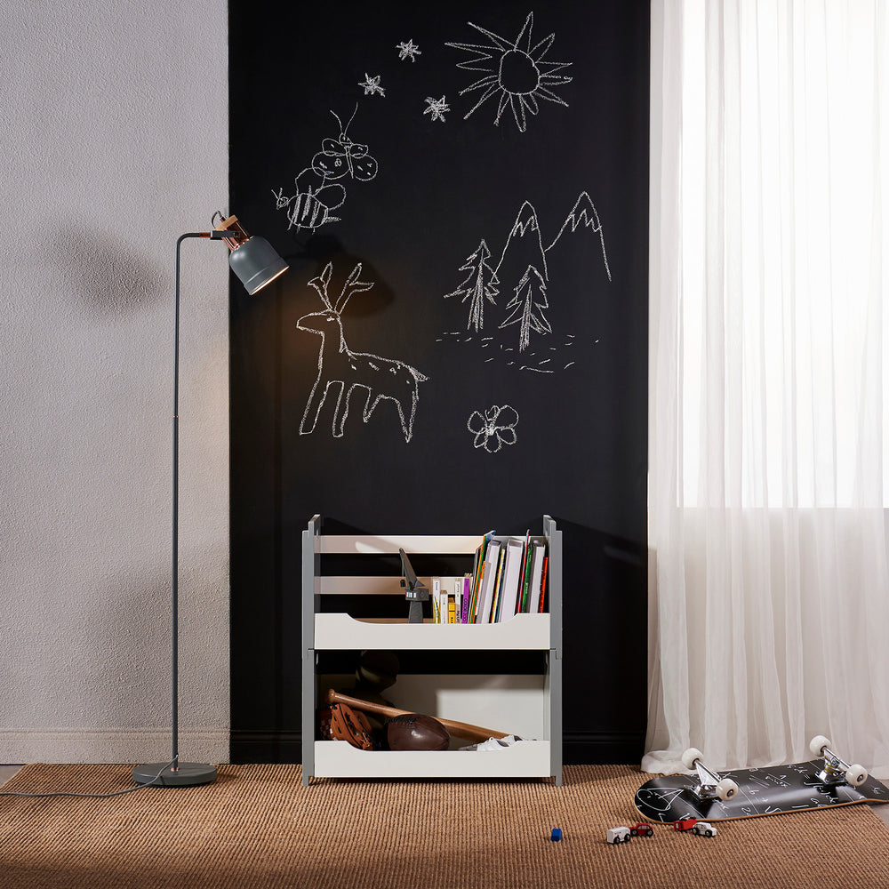A minimalistic children's room corner with a black chalkboard wall featuring simple white drawings, next to a Teamson Home Cubo Stacking Storage Unit in White/Gray with toys and a standing lamp for a modern look.