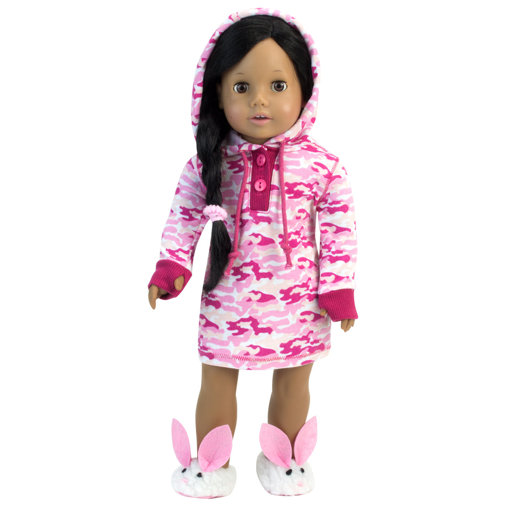 A black-haired 18" doll dressed in a pink camo print dress with fuzzy white bunny slippers
