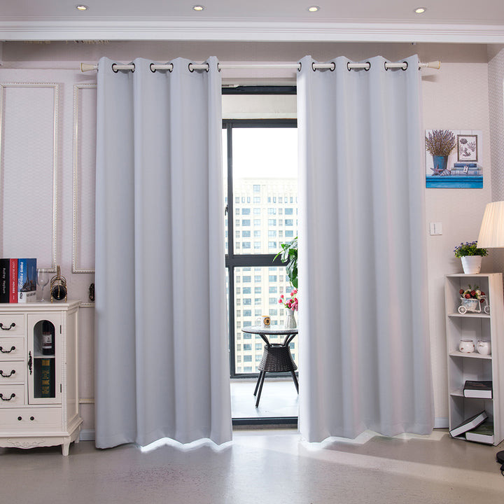 A modern living room with open Teamson Home 63" Corinth Premium Solid Insulated Thermal Blackout Window Curtain Panels with Grommets, Cloud Gray revealing a window view of a cityscape.