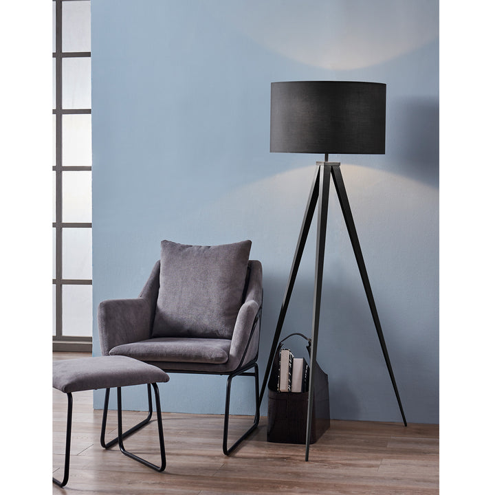 A modern, versatile reading nook featuring a gray armchair and ottoman with a Teamson Home Romanza 60" Postmodern Tripod Floor Lamp with Drum Shade, Matte Black in a room with blue walls.