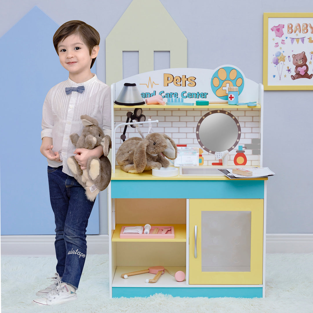 A child stands beside a Teamson Kids Little Helper Wooden Pet Care and Veterinary Clinic Playset, holding stuffed animals.