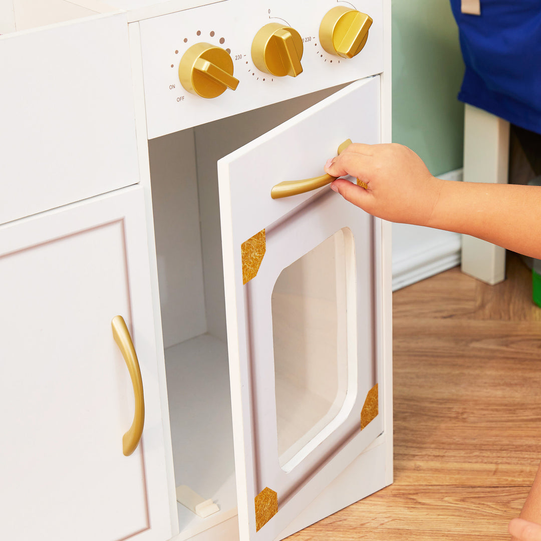 A young boy opens the door underneath the stovetop on his play kitchen.