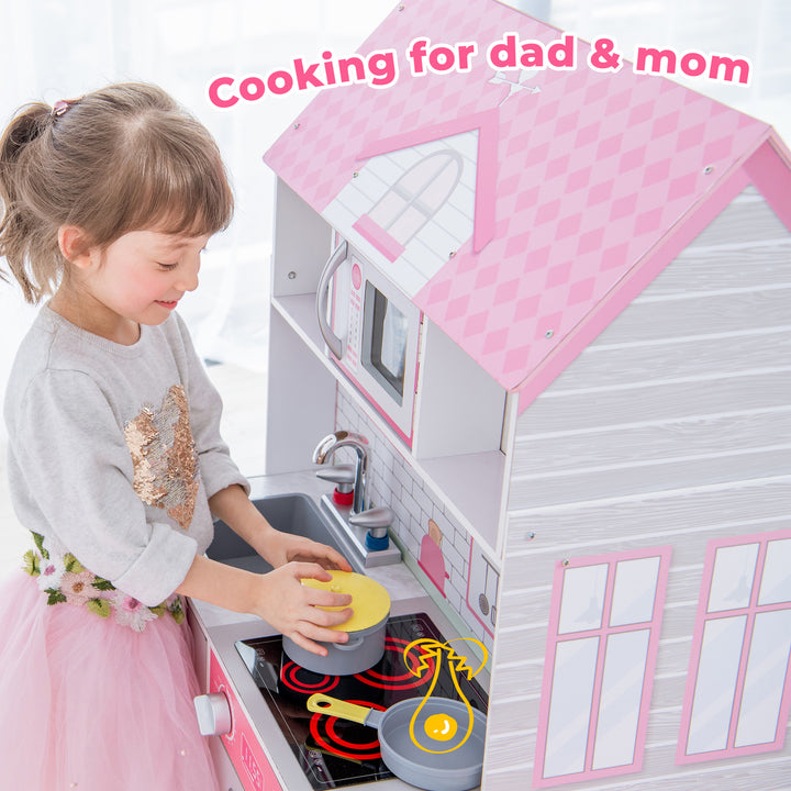 A young girl plays with the Teamson Kids Ariel 2-in-1 Double-Sided Play Kitchen with Accessories and Furnished Dollhouse for 12" Dolls, Pink, pretending to cook.