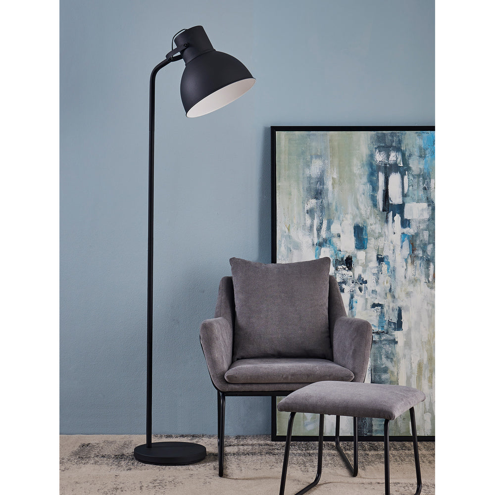 A chair and a Teamson Home Aaron 70.8" Metal Floor Lamp with Adjustable Shade, Black in a room.