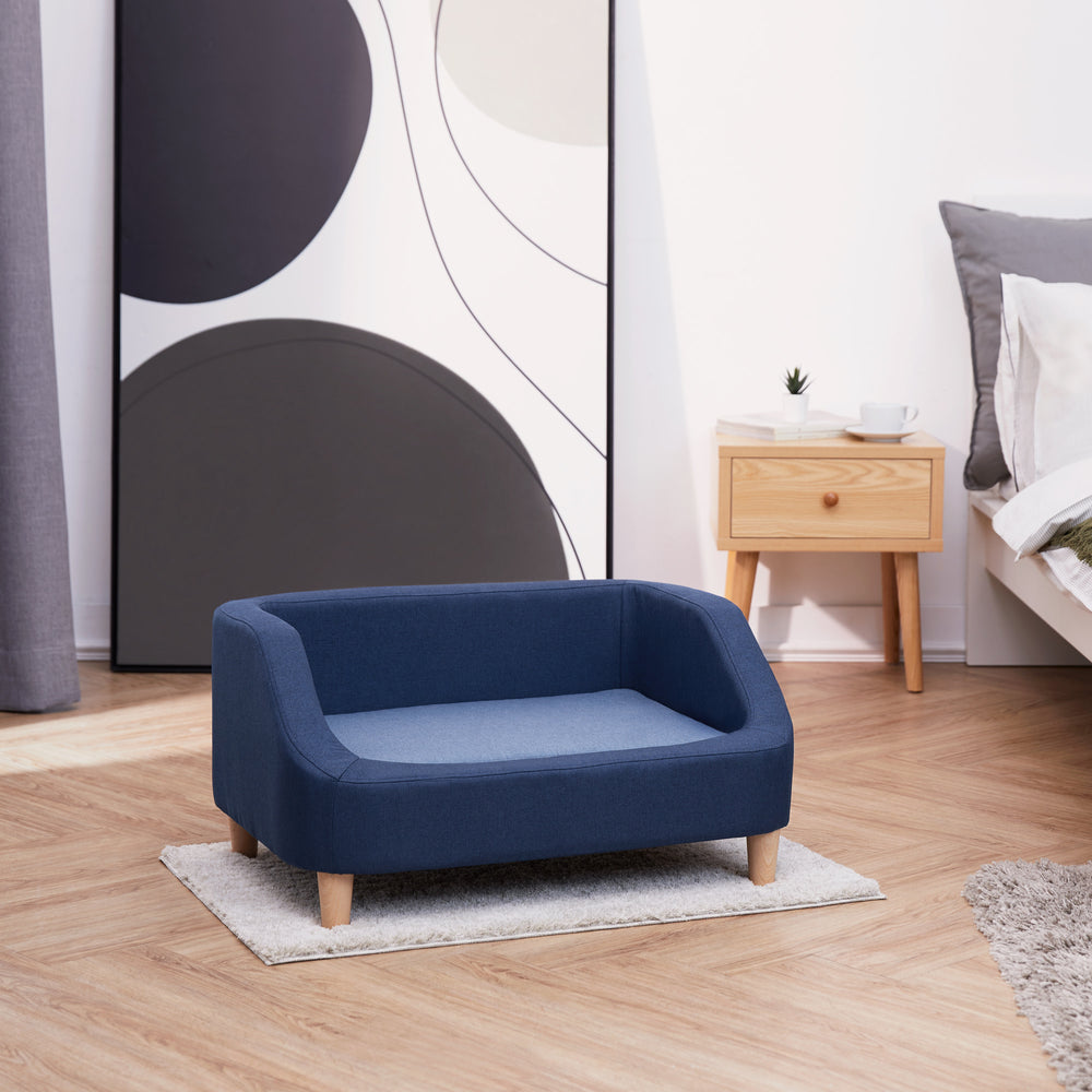 The Bennett Linen Sofa Pet Bed in Navy/Light Blue in a modern-styled bedroom.