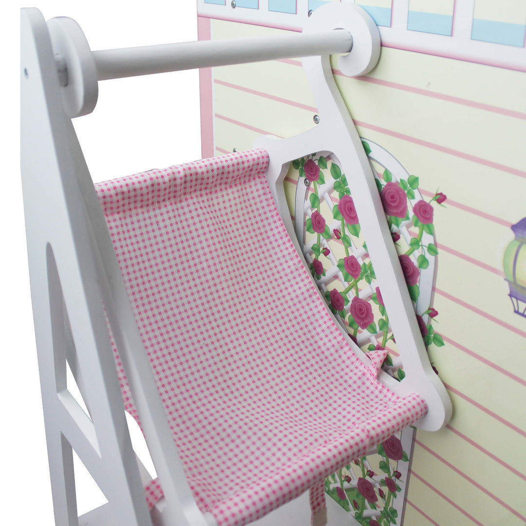 A close-up of the separate baby doll swing with a white frame and pink gingham seat next to the dollhouse.