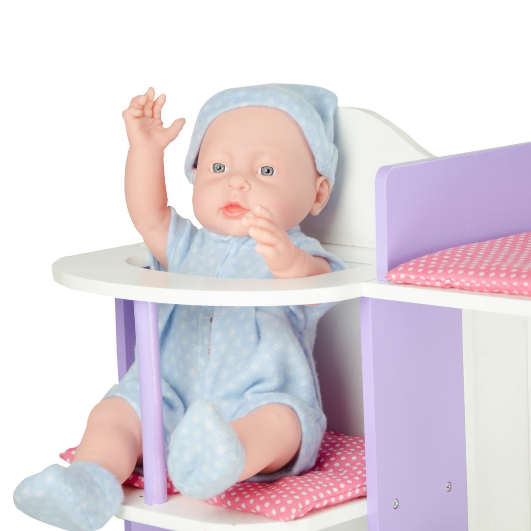 A close-up of a baby doll dressed in blue sitting in the high chair portion of the changing station.