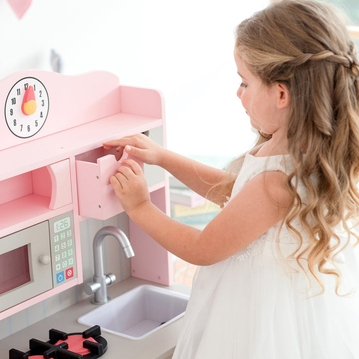 A child enjoys their Teamson Kids Little Chef Florence Classic Play Kitchen, Pink/Gray.