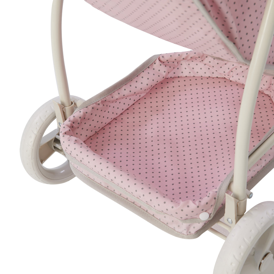 A close-up of the storage space on the convertible baby doll stroller, pink with gray polka dots.