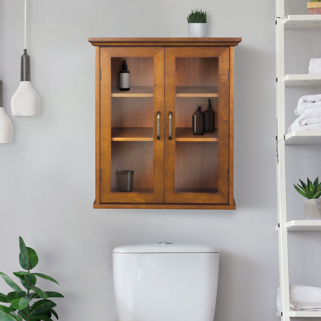 A Teamson Home Avery Oiled Oak Removable Wall Cabinet over a white toilet in a bathroom with toiletries inside