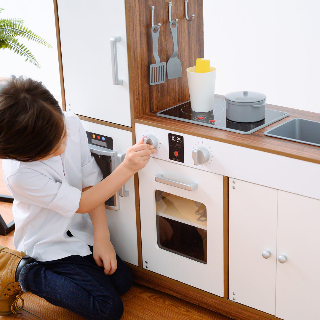 Child playing with the oven knobs on a Teamson Kids Little Chef Palm Springs Classic Kids Play Kitchen with Accessories, Natural/White.