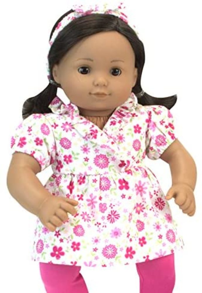 A 15" Doll with dark hair and eyes dress in a white with pink floral print top and matching headband and pink leggings.