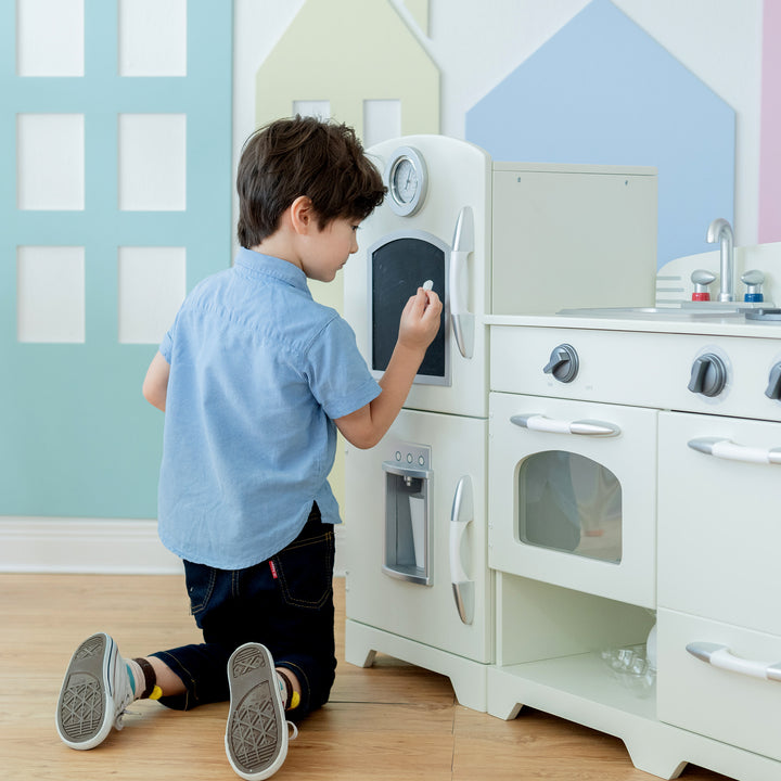 A child playing with an easy-to-clean Teamson Kids Little Chef Fairfield Retro Kids Kitchen Playset with Refrigerator, Ivory.
