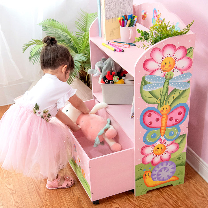 A girl in a tutu is placing a stuffed animal in the storage drawer, illustrating how large it is.