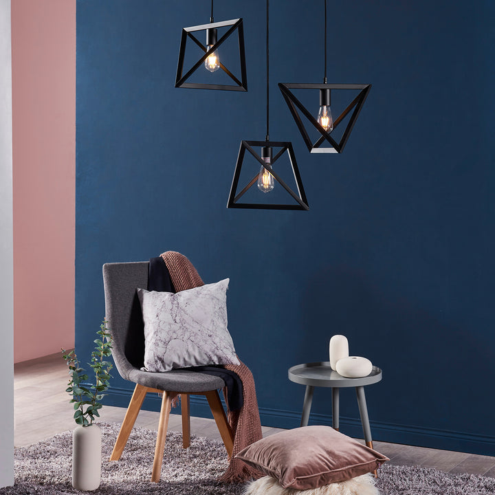 Modern interior design with the Teamson Home Armonia Geometric Pendant Lamp, Black, a stylish grey armchair with durable cushions, and a side table against a blue wall.