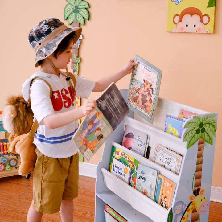 A boy is holding a couple of books next to a Sunny Safari book case.