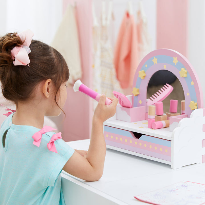 A little girl is playing with a Teamson Kids Little Dreamer Wooden Tabletop Vanity Set with 9 Play Accessories, Pink.