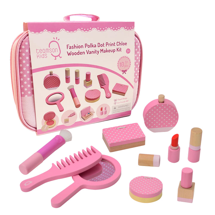 The make-up kit in its packaging with the contents on the table in front of it:  brush, comb, hand-held mirror, eyeshadow pallet, perfume, two lipstick tubes, compact and nail polish.