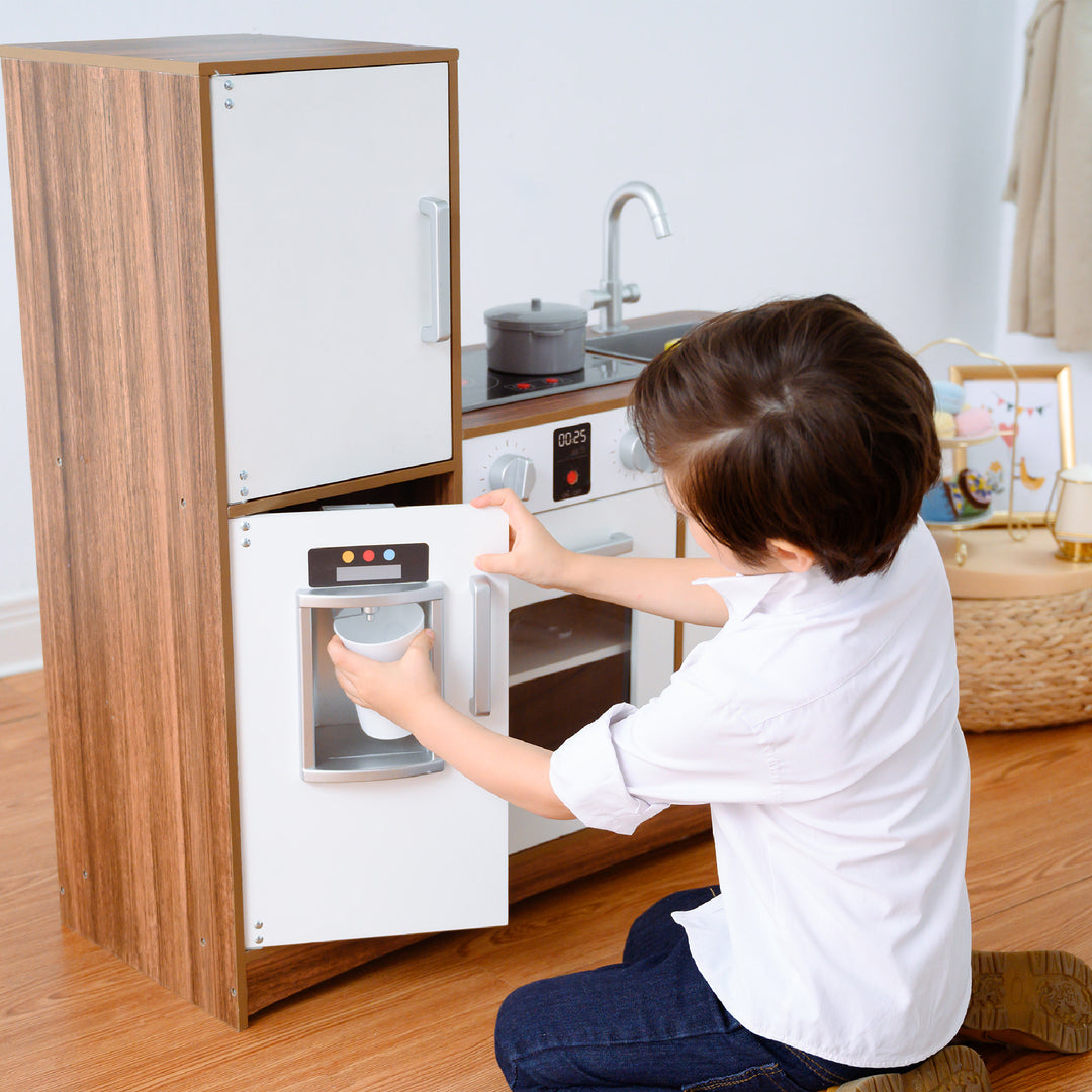 Child playing with a Teamson Kids Little Chef Palm Springs Classic Kids Play Kitchen with Accessories, Natural/White.