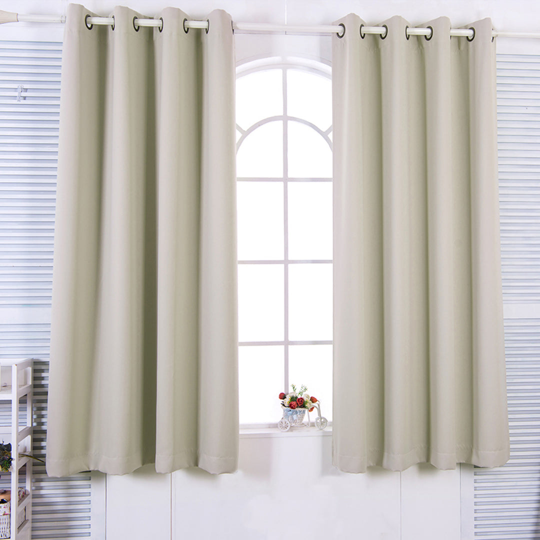 63" Tripoli Premium Solid Insulated Thermal Blackout Grommet Window Panels, Oyster curtains hanging on a window with white blinds and a vase of flowers on the windowsill.
