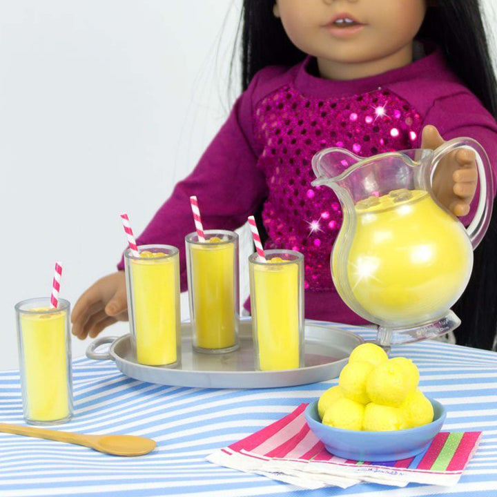 A doll holding Sophia’s Fresh Lemonade Drink Set with Pitcher for 18" Dolls.