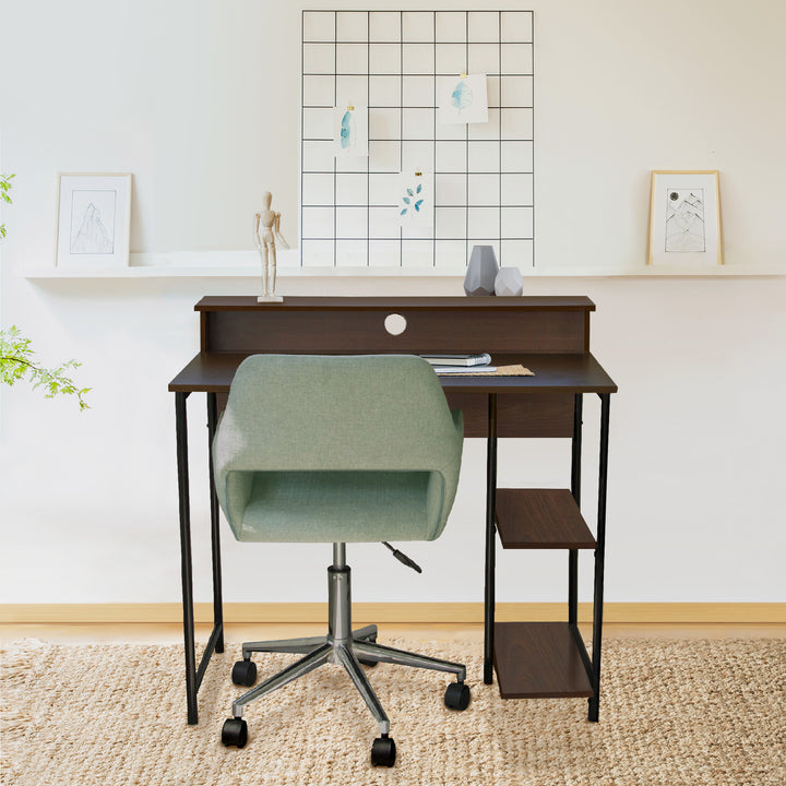 Teamson Home Computer Desk with Metal Base and Storage, Walnut Finish/Black in a room with a green chair.
