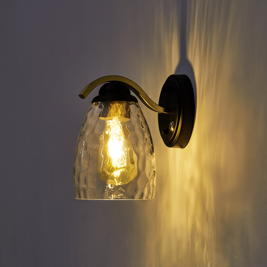 Teamson Home Heidi Wall Sconce with Clear Hammered Glass Cloche Shade, Black/Brass on in a dark room
