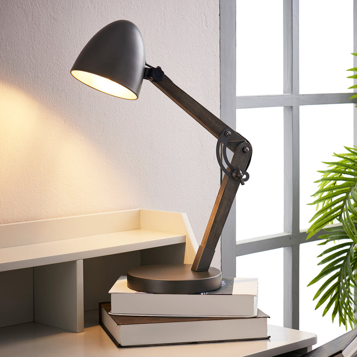 A Teamson Home Lexi Modern Reading Table Lamp with Black Shade and Brushed Steel Finish with books on top of it.