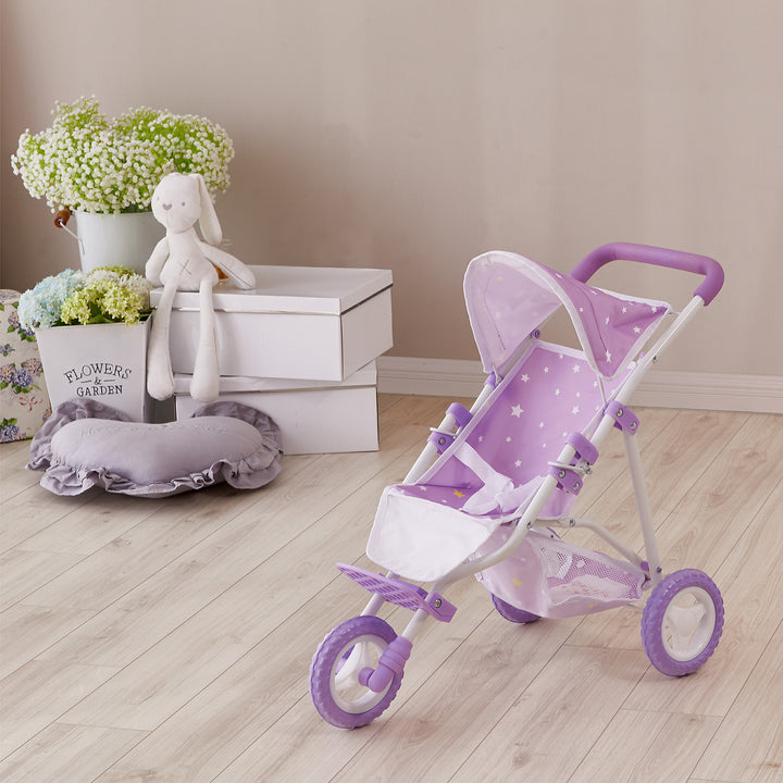 A purple with white stars baby doll jogging stroller with purple wheels and a white frame in a room with a stuffed bunny and some decorative accents.