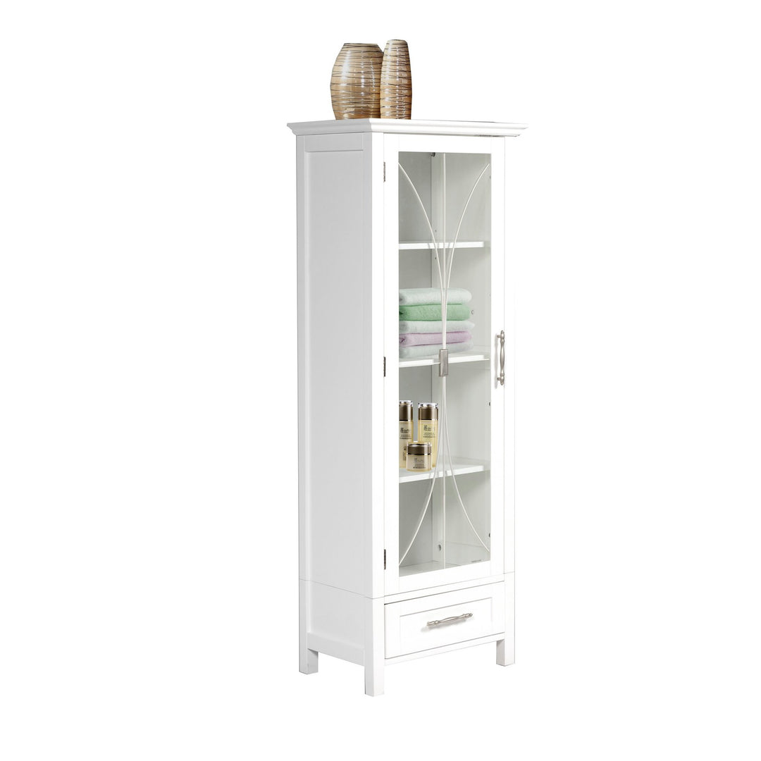 A side view of a White Teamson Home Delaney Free Standing Tall Linen Cabinet Tower with Glass Panel Door with a Storage Drawer with items on top and towels and toiletries inside