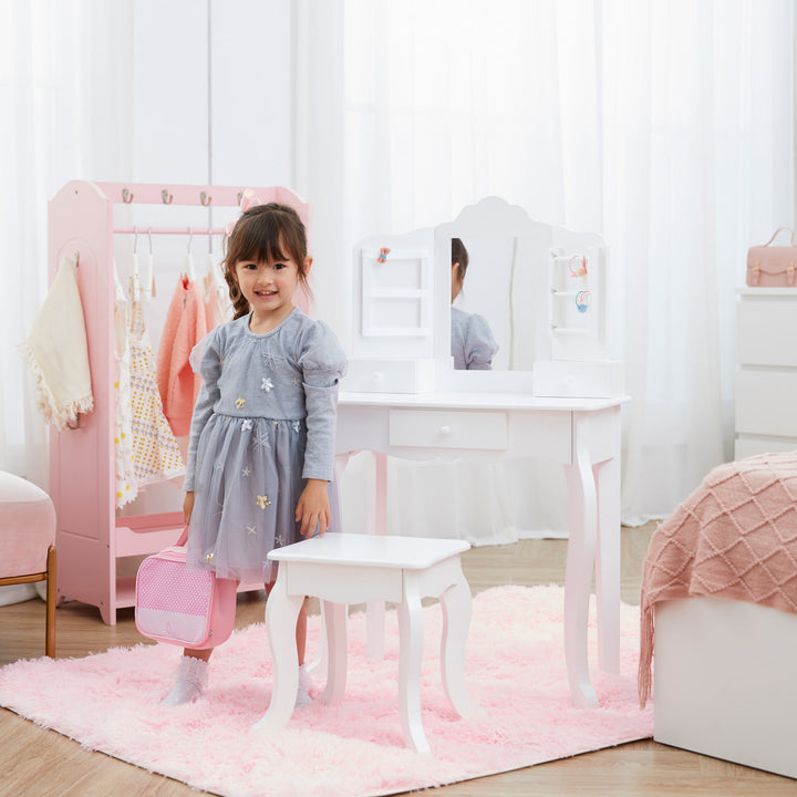 A little girl standing next to the white vanity set with matching stool, storage drawers, and a mirror with storage racks on either side in a bedroom.