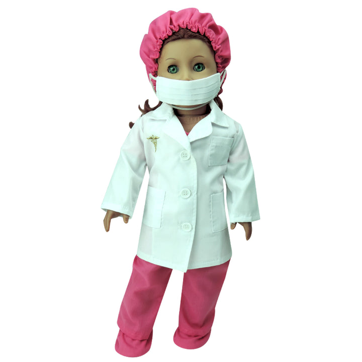 A doll dressed in pink surgical scrubs, cap, and shoe covers, a white lab coat, and a blue face mask.