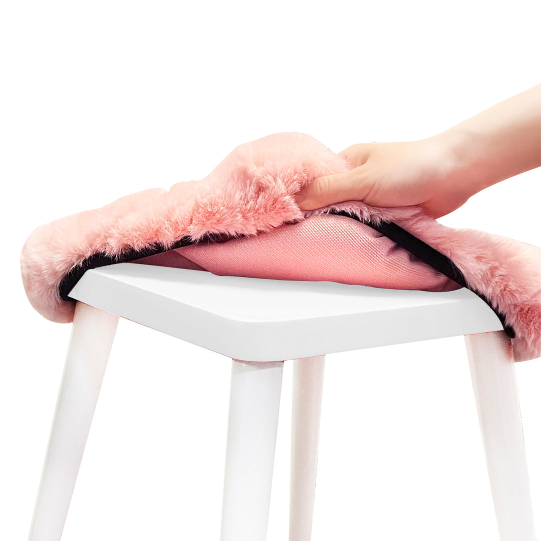 View of the pink fur cover being pulled off a white stool.