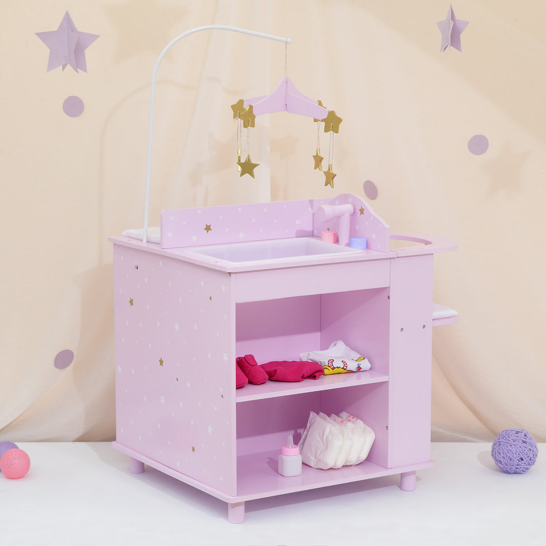 A baby doll changing station in purple with white and gold stars with a view of the sink, mobile, and storage shelves with items on them.